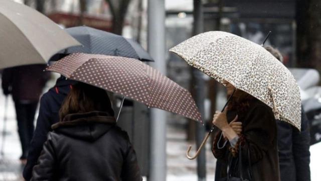 Varias personas pasean por Barcelona con paraguas a causa de las lluvias