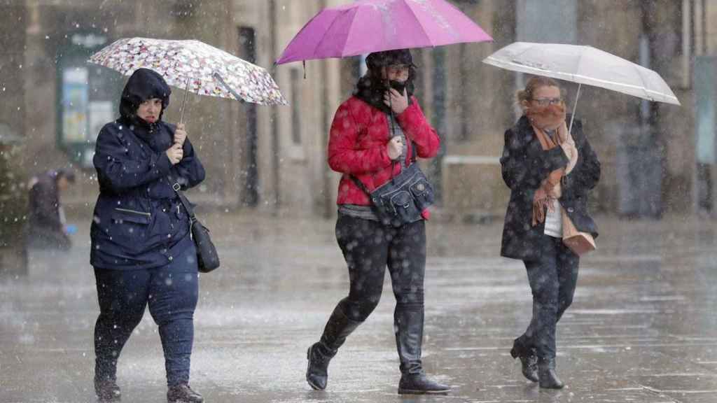 Tres personas cubiertas con paraguas durante una jornada de lluvias en Barcelona
