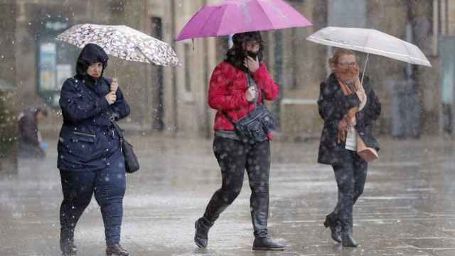 Tres personas cubiertas con paraguas durante una jornada de lluvias en Barcelona