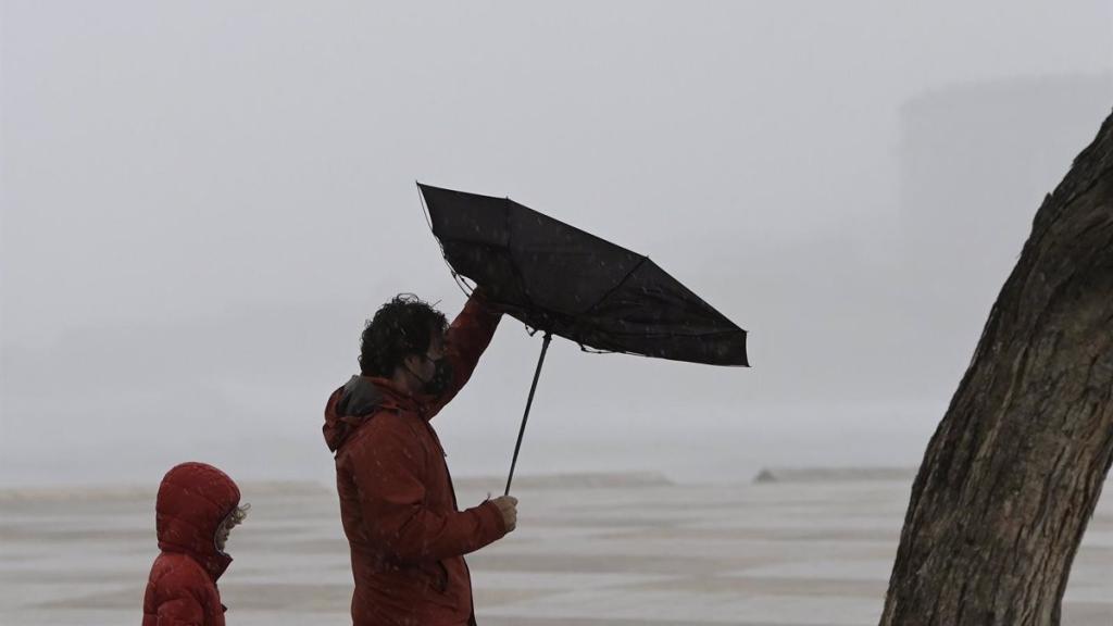 Un hombre tiene problemas con su paraguas por el viento