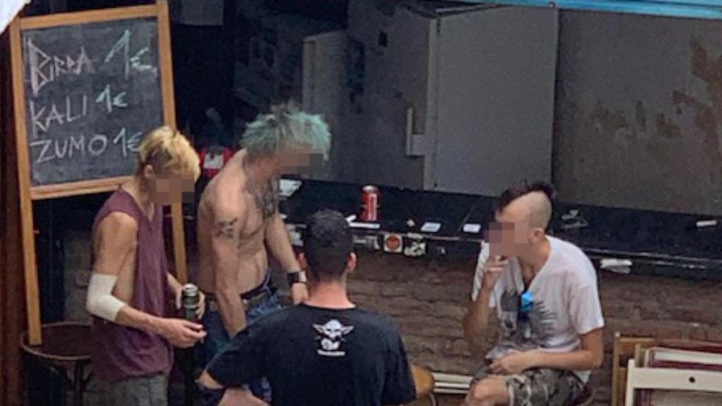 Varias personas consumen bebidas en el bar de Can Vies, al lado de una pizarra en la que se muestran los precios