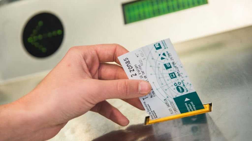 Un usuario del metro de Barcelona validando un billete de cartón en las máquinas