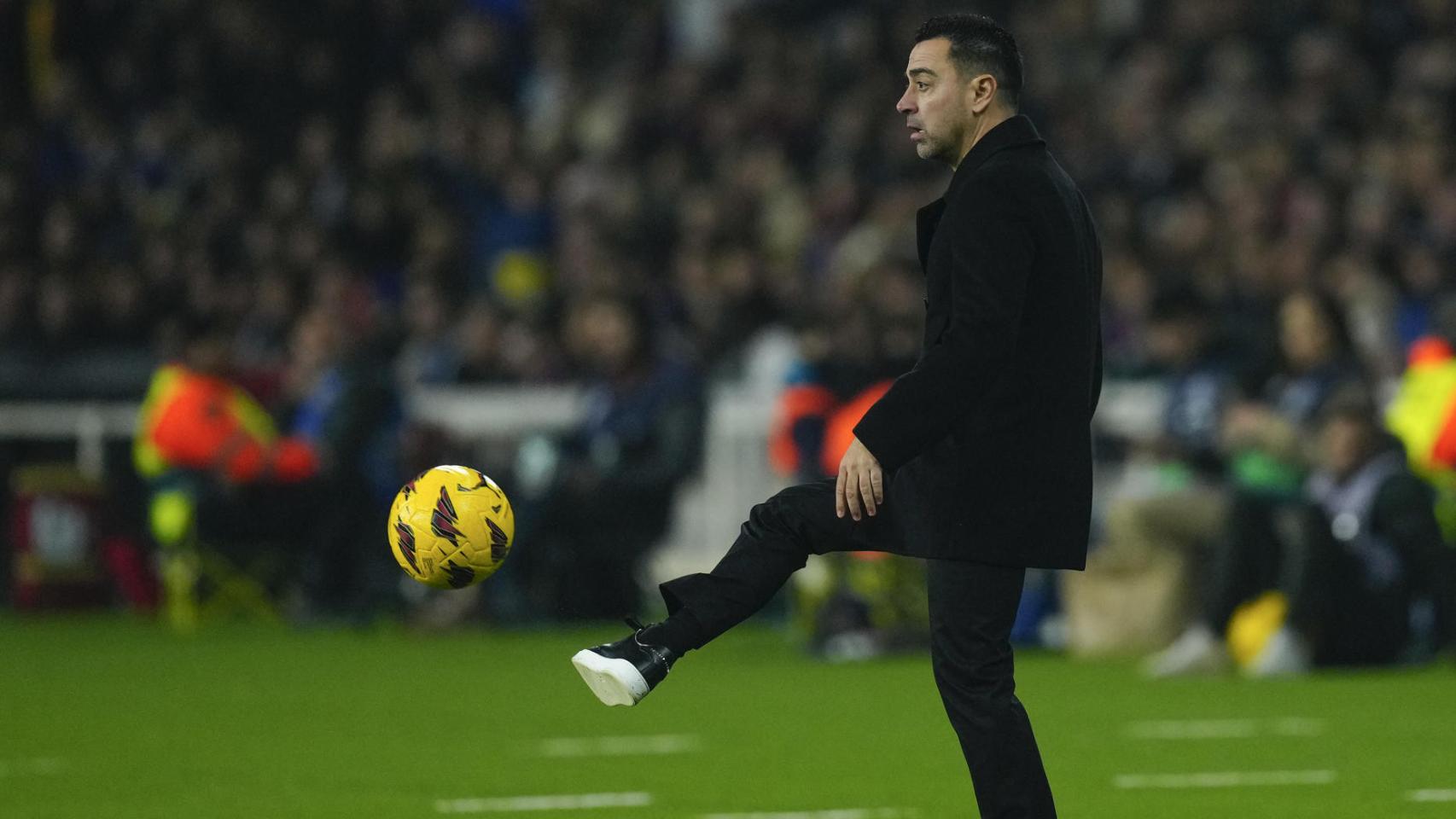 Xavi Hernández, pasando el balón desde el banquillo del Barça