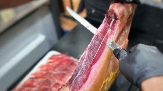 Un camarero preparando una tapa de jamón ibérico