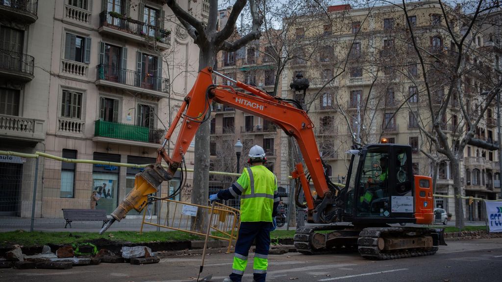Un obrer i una màquina excavadora treballen a les obres per unir el tramvia per la Diagonal