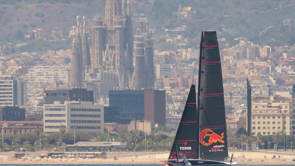 Imagen de un monocasco de la Copa América de vela con la Sagrada Familia de fondo