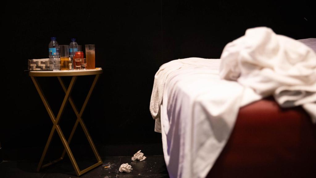Una cama deshecha y una mesa con bebidas en un prostíbulo de Barcelona
