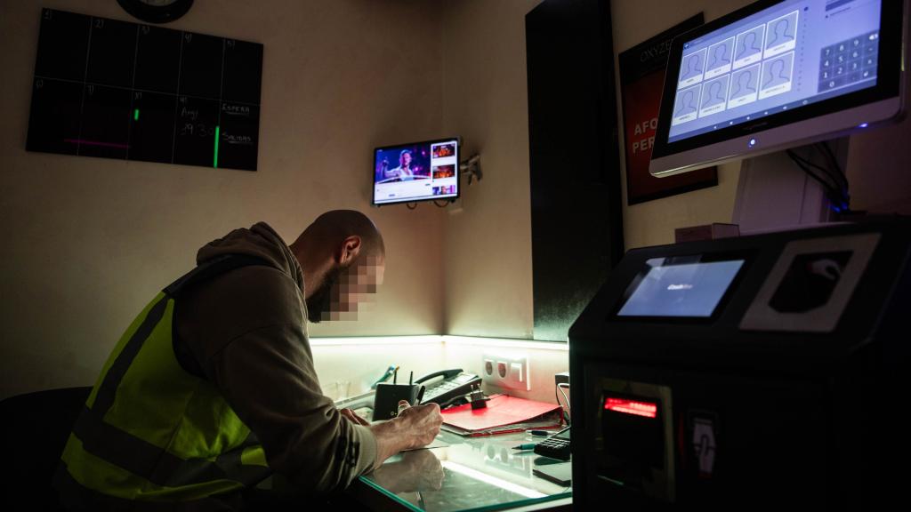 Un agente de la Policía Nacional comprueba la documentación de las mujeres durante una inspección de la Policía Nacional en un prostíbulo de Barcelona