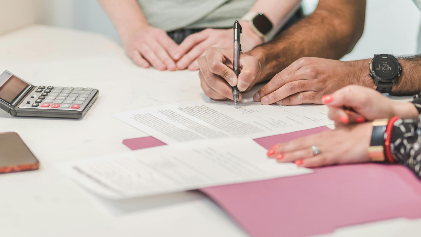 Diversas personas haciendo cálculos en su declaración de la renta