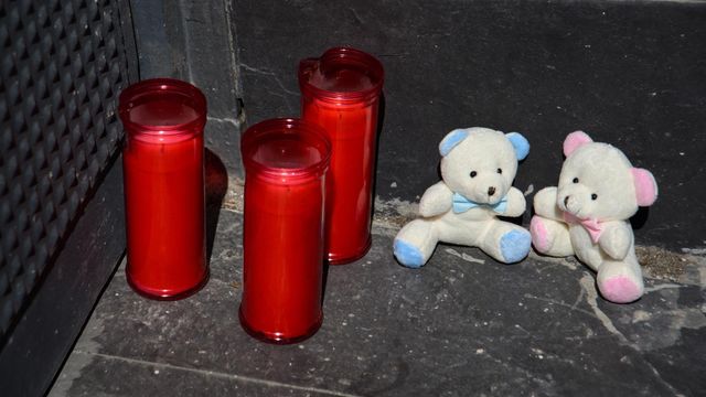 Tres velas y dos osos de peluche en la puerta del garaje de la vivienda donde un hombre ha matado presuntamente a su mujer y sus dos hijos menores