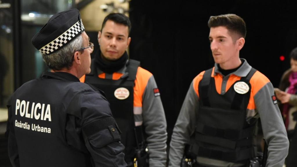 Vigilantes de seguridad junto a un agente de la Guardia Urbana en Barcelona