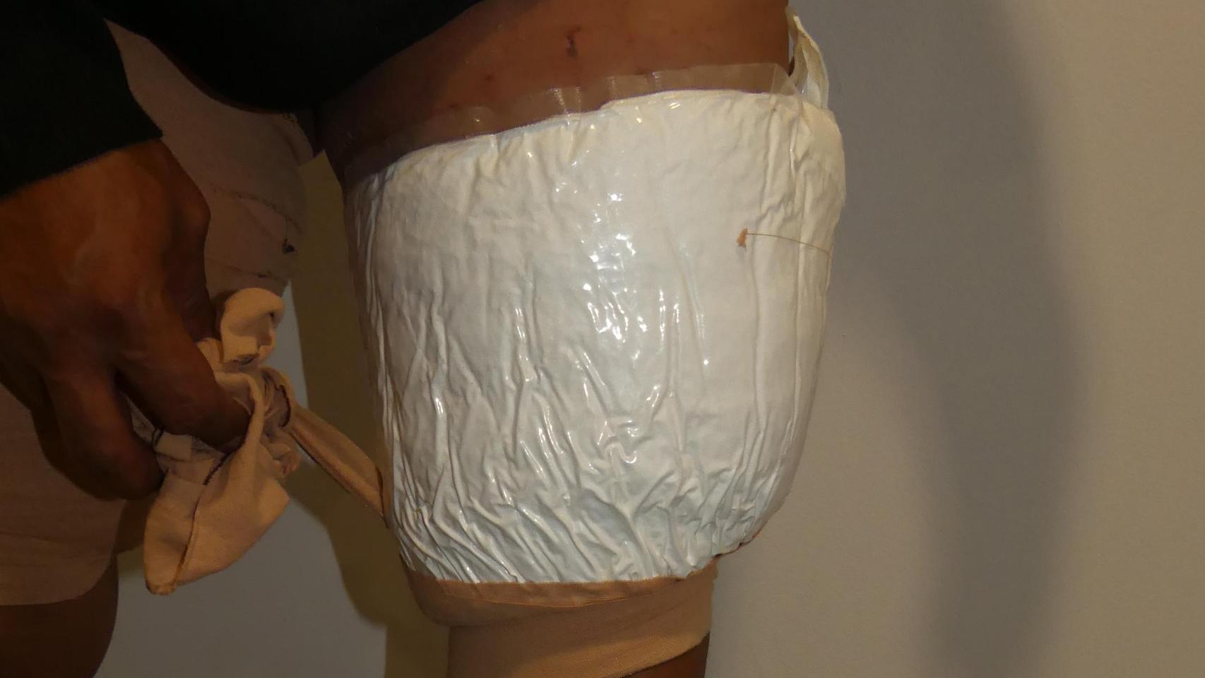 Uno de los detenidos destapa los paquetes de cocaína que se ha adherido al cuerpo