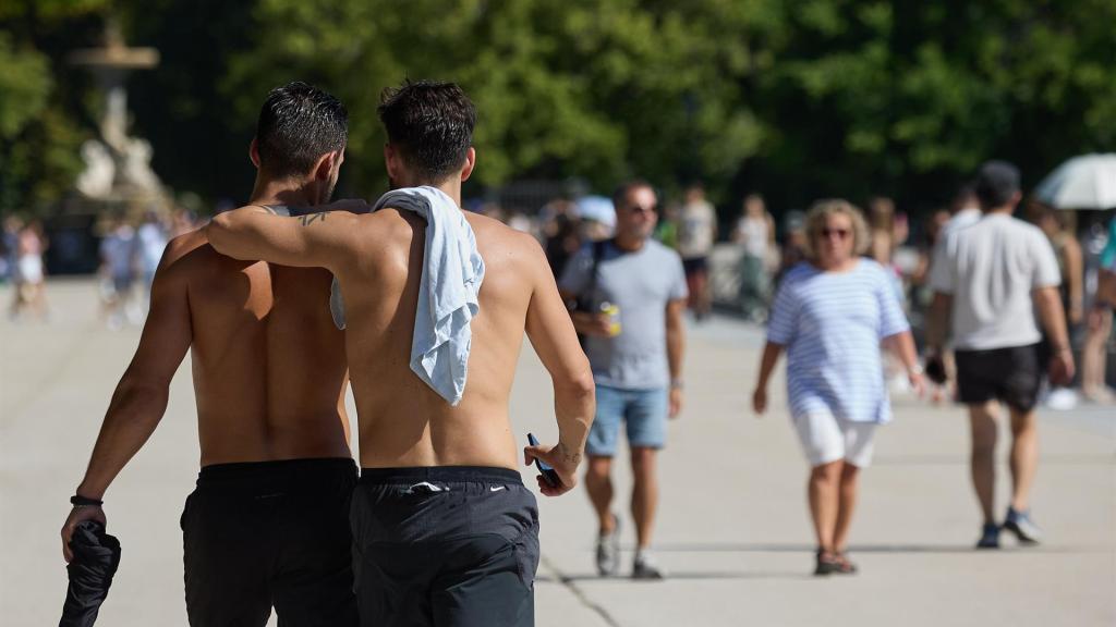 Dos hombres sin camiseta pasean por Barcelona durante la ola de calor