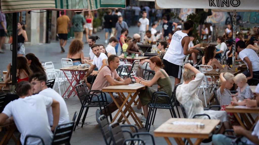 Diverses persones assegudes en terrasses a la plaça dels Àngels del Raval a Barcelona