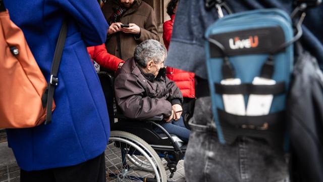 Una persona mayor en silla de ruedas frente a una residencia en Barcelona