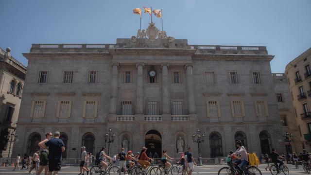 Varias personas caminan delante del edificio del Ayuntamiento de Barcelona.