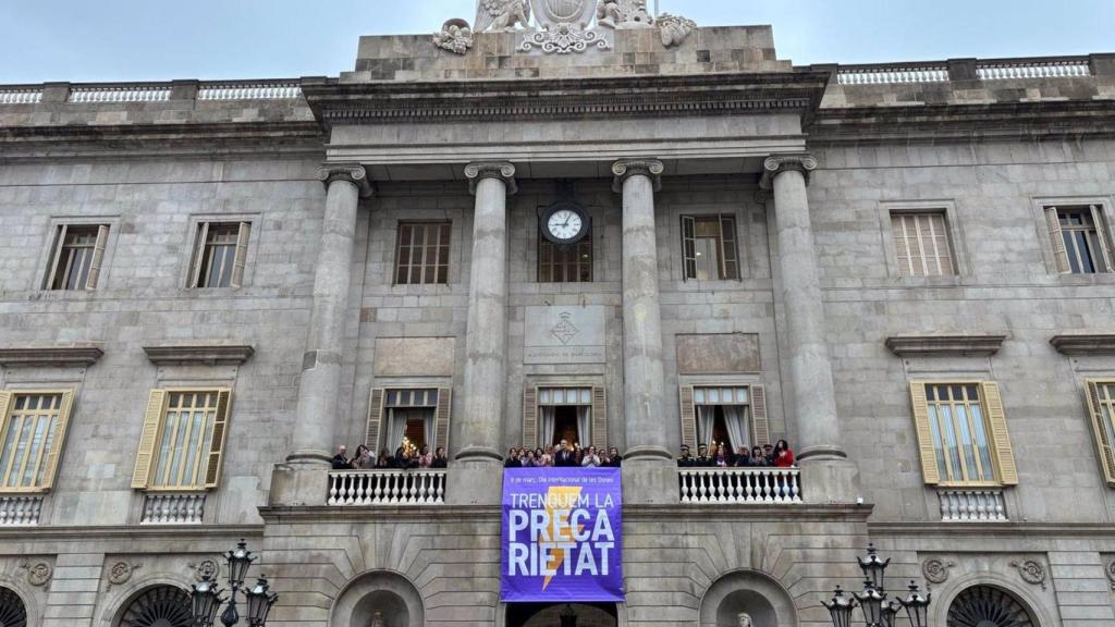 L'alcalde Jaume Collboni, representants del govern, de grups polítics i d'entitats han estès una pancarta al balcó de l'Ajuntament amb el lema d'aquest any per al 8M 'Trenquem la precarietat'