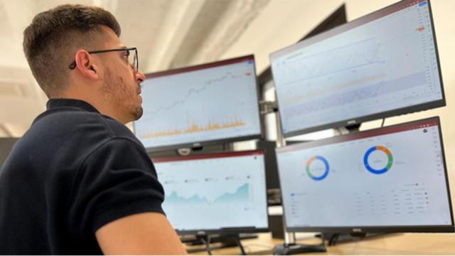 Trader frente a varias pantallas con valores bursátiles