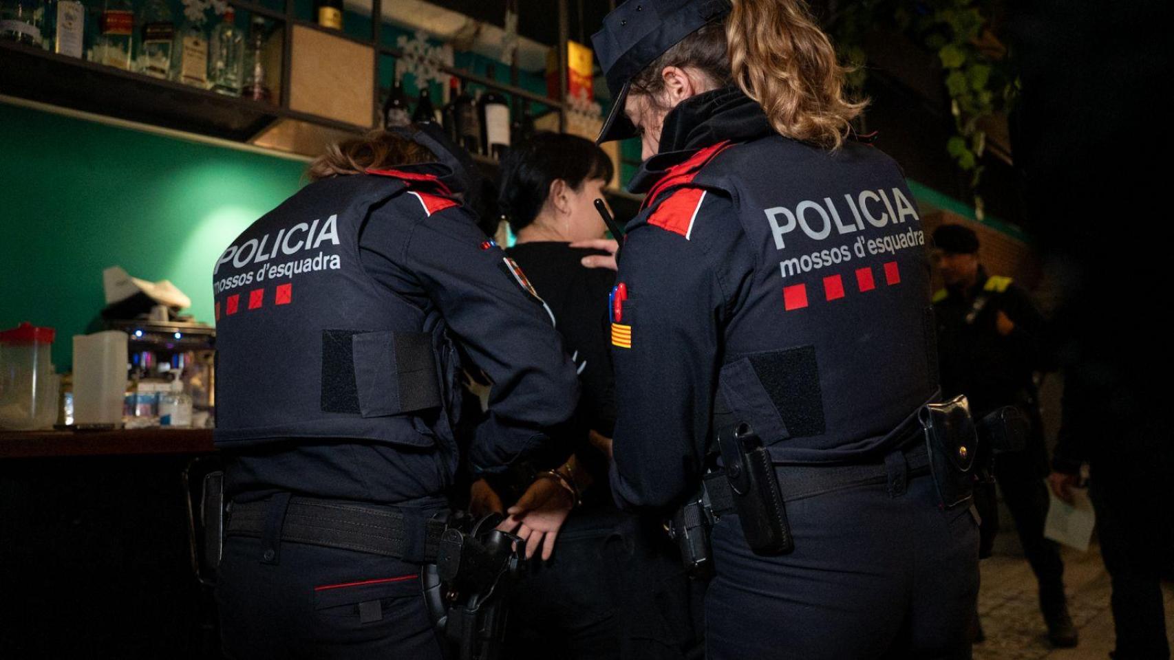 Dos agentes de los mossos esposando a una de las detenidas del dispositivo en Badalona
