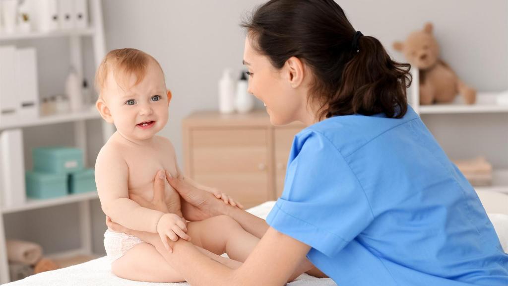 Lactante que es ayudado por una adulta a sedestarse