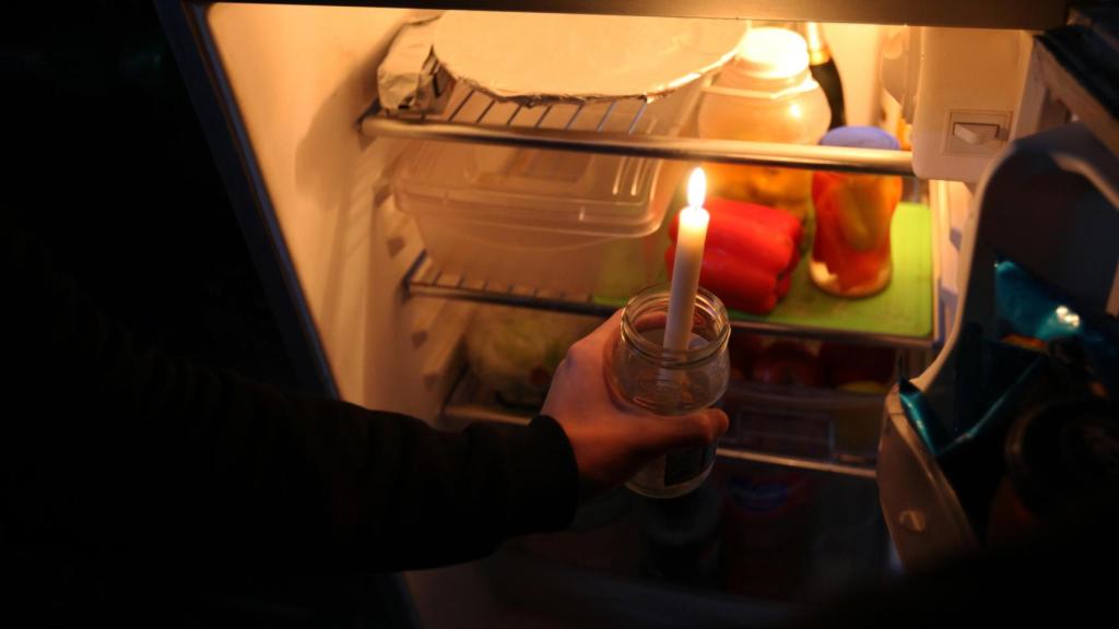 Una persona sostiene una vela frente a una nevera