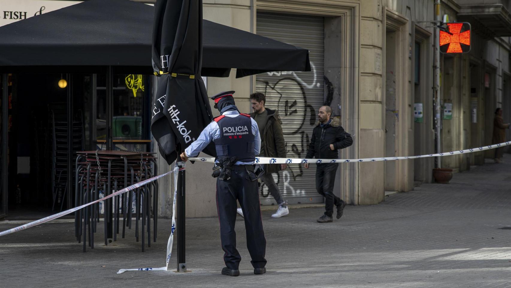 Un agente acordona la zona donde se encontró un cadáver en un contenedor del centro de Barcelona