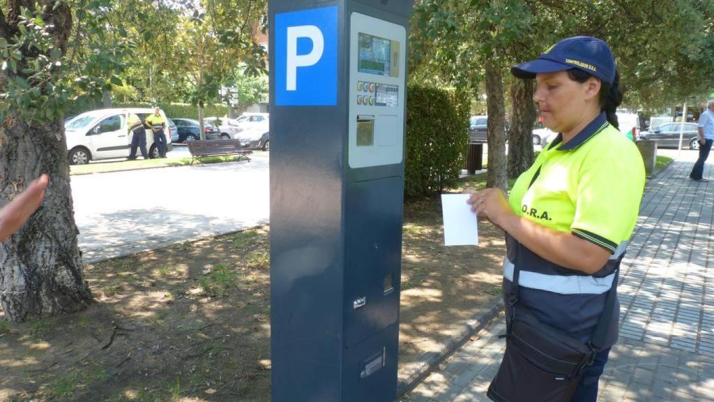 Una revisora frente a un parquímetro