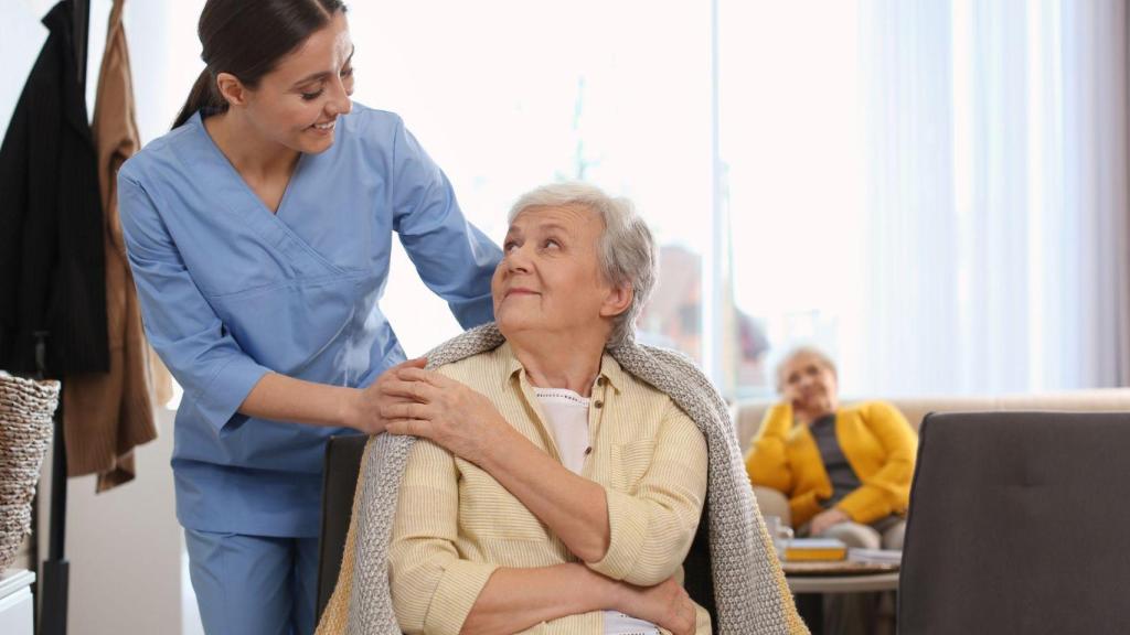 Una persona major amb l'ajuda d'una professional sanitària