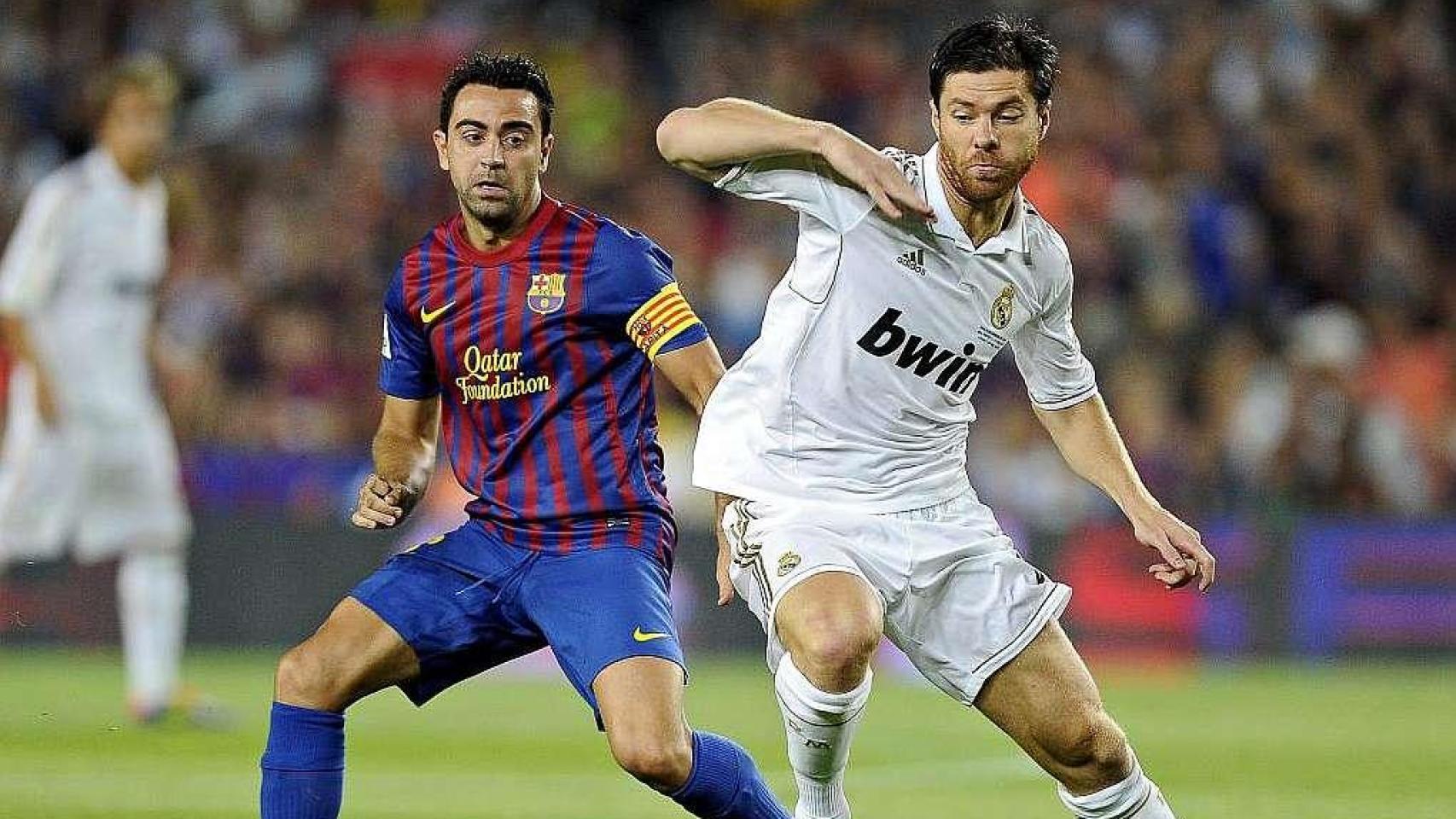Xabi Alonso y Xavi Hernández disputan un balón durante su etapa como profesionales en Madrid y Barça