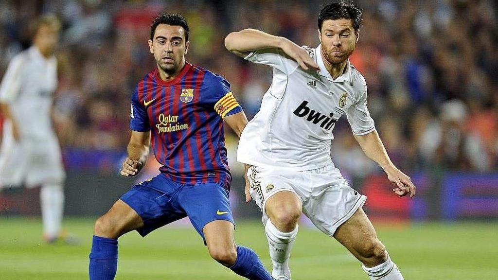 Xabi Alonso y Xavi Hernández disputan un balón durante su etapa como profesionales en Madrid y Barça