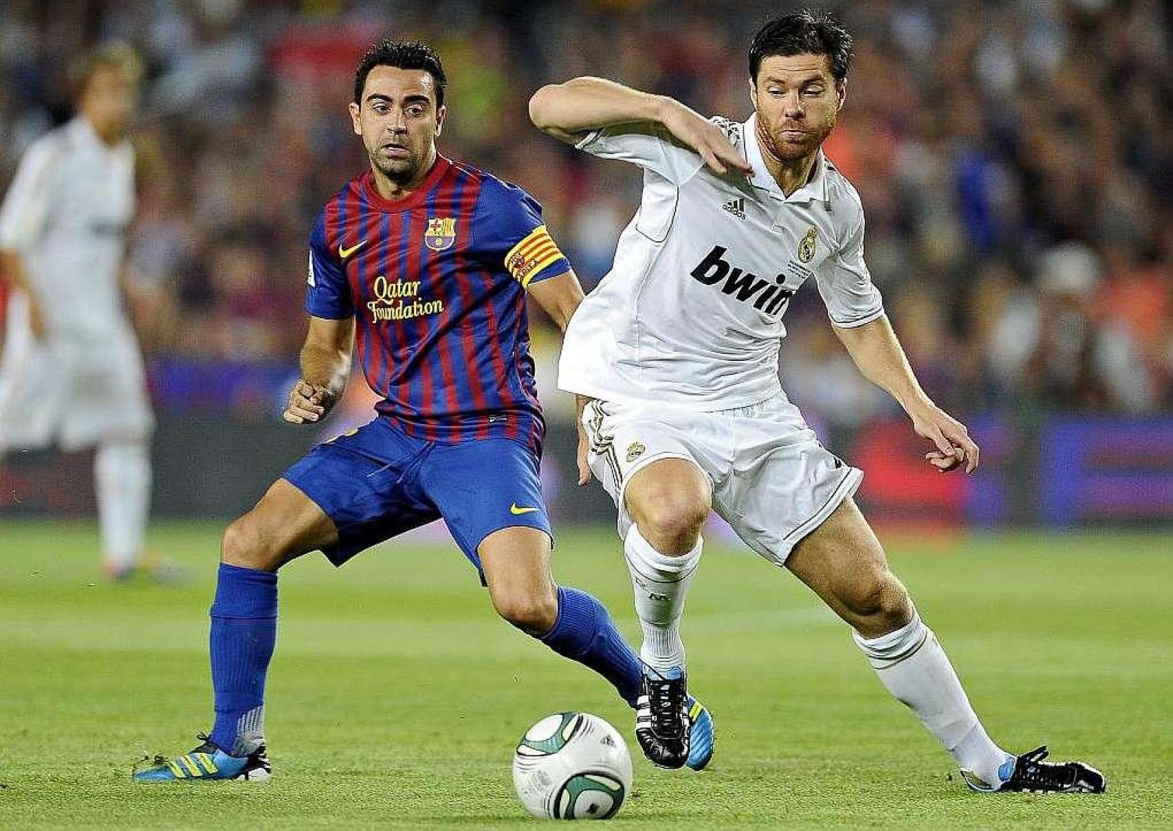 Xabi Alonso y Xavi Hernández disputan un balón durante su etapa como profesionales en Madrid y Barça