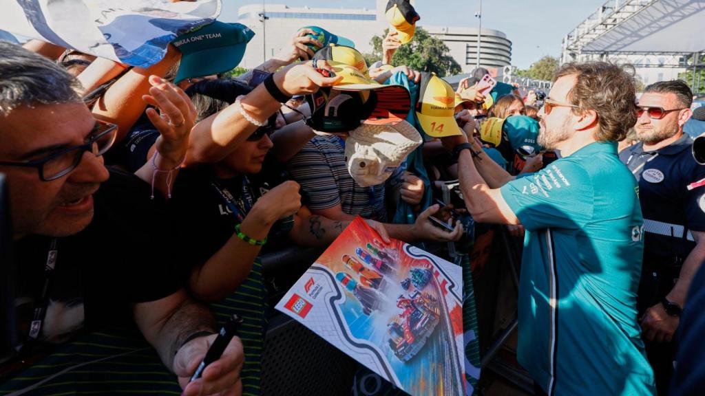 Fernando Alonso firmando gorras de los aficionados
