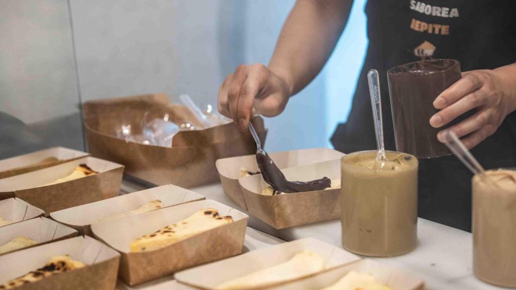 Treballador de '99Cheesecake' elaborant un dels trossos de tarta