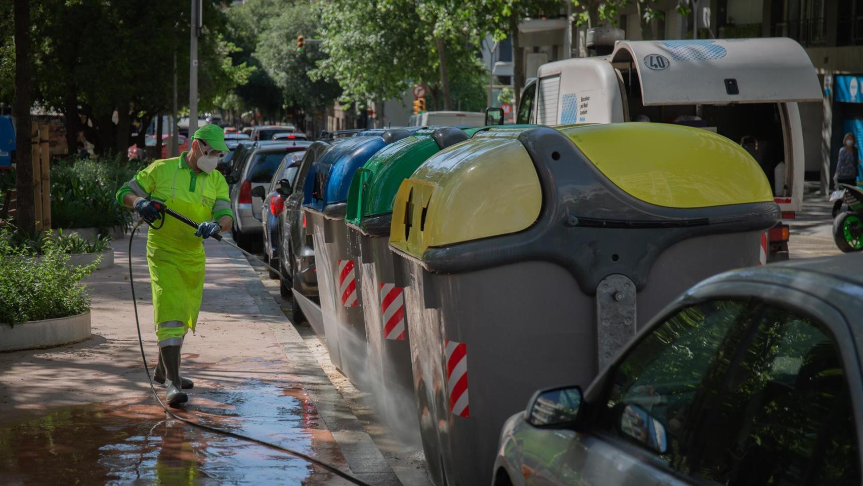 Un operario de limpieza del servicio municipal desinfecta un contenedor amarillo de basura tras la reincorporación de 1.000 operarios de limpieza durante la fase 0 de la desescalada en la ciudad. Como anunció el concejal de Emergencia Climática