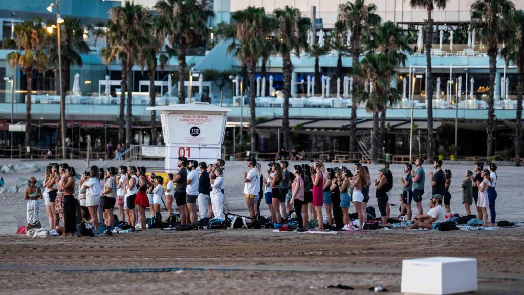 Un grupo de personas medita en la playa de Sant Sebastià de Barcelona