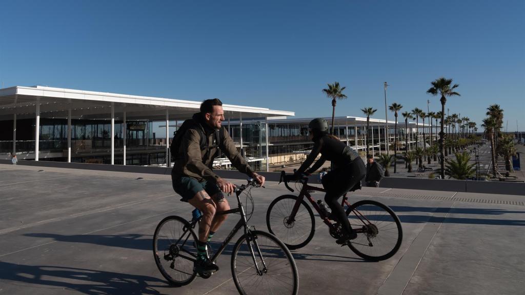 Dos personas circulan en bicicleta por el Port Olímpic, en Barcelona