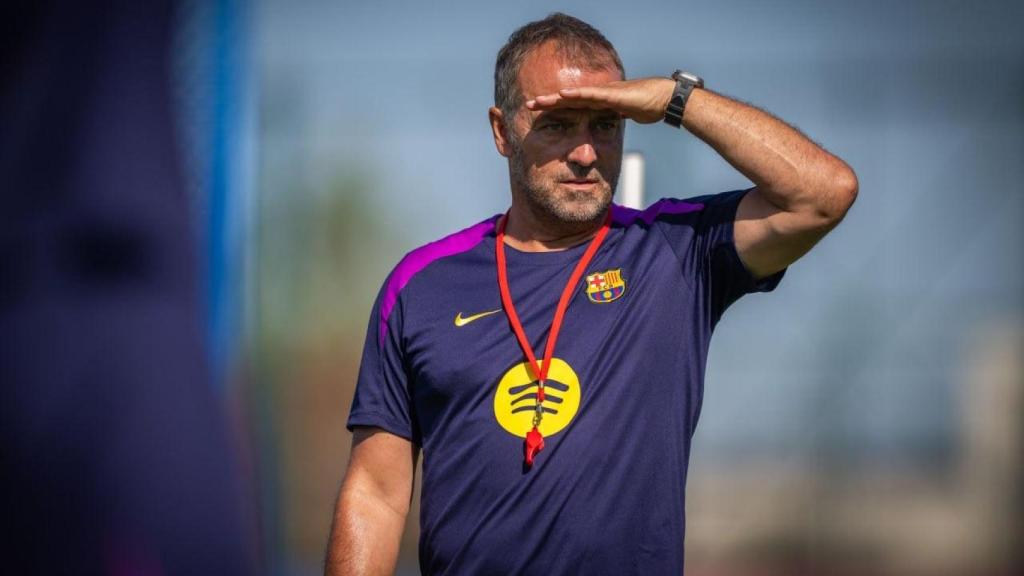 Hansi Flick se tapa el sol de la cara con la mano para observar a sus futbolistas