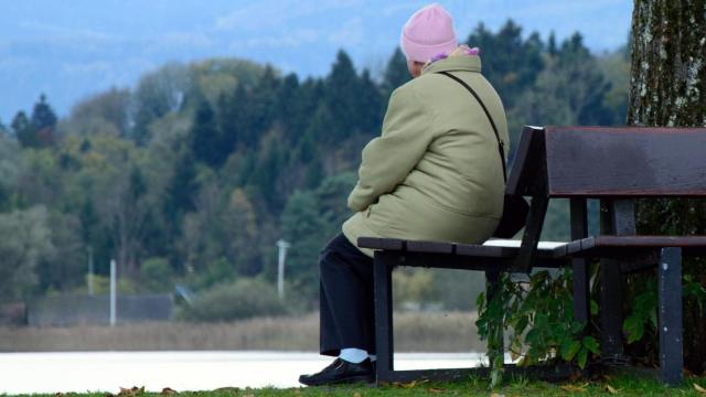 Una persona mayor sentada en un banco en una imagen de Canva