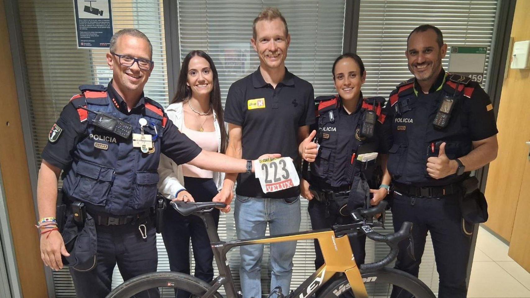 Imagen del ciclista Magnus Cort con la bicicleta recuperada y los agentes de los Mossos