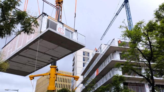 Imagen del momento en que se añade un módulo tridimensional al edificio en construcción de una promoción de vivienda protegida en Barcelona