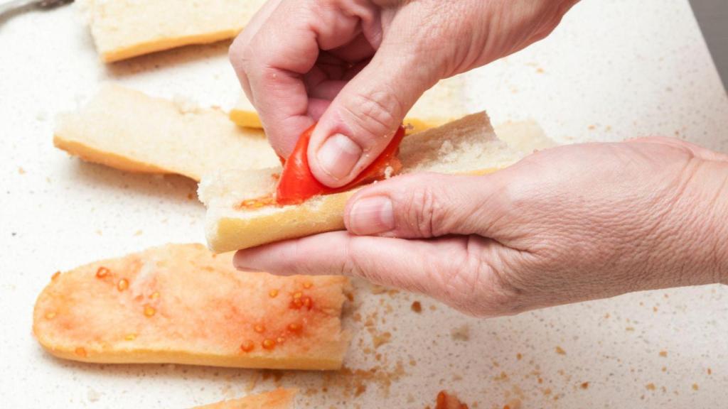 Persona refregando el tomate en el pan