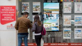 Personas mirando el escaparate de la inmobiliaria / EFE