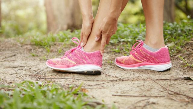 Una corredora se queja de dolor en un tobillo