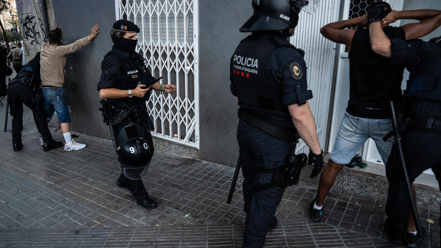 Agentes de la Brimo de los Mossos d'Esquadra cacheando a dos personas en el marco de un 'pla Kanpai'