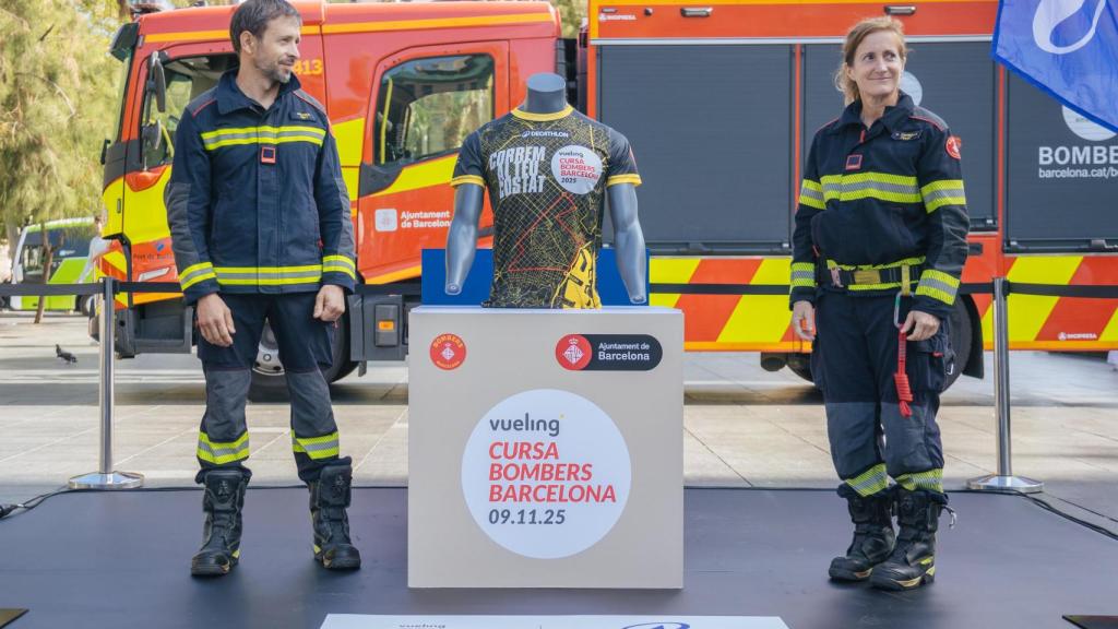 Dos bomberos descubriendo la camiseta oficial de la carrera