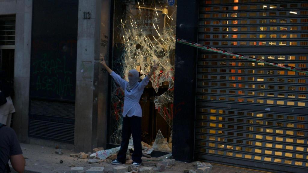 Manifestante ante un comercio vandalizado en Barcelona