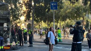 Una turista se hace una foto frente al autobús calcinado en el centro de Barcelona