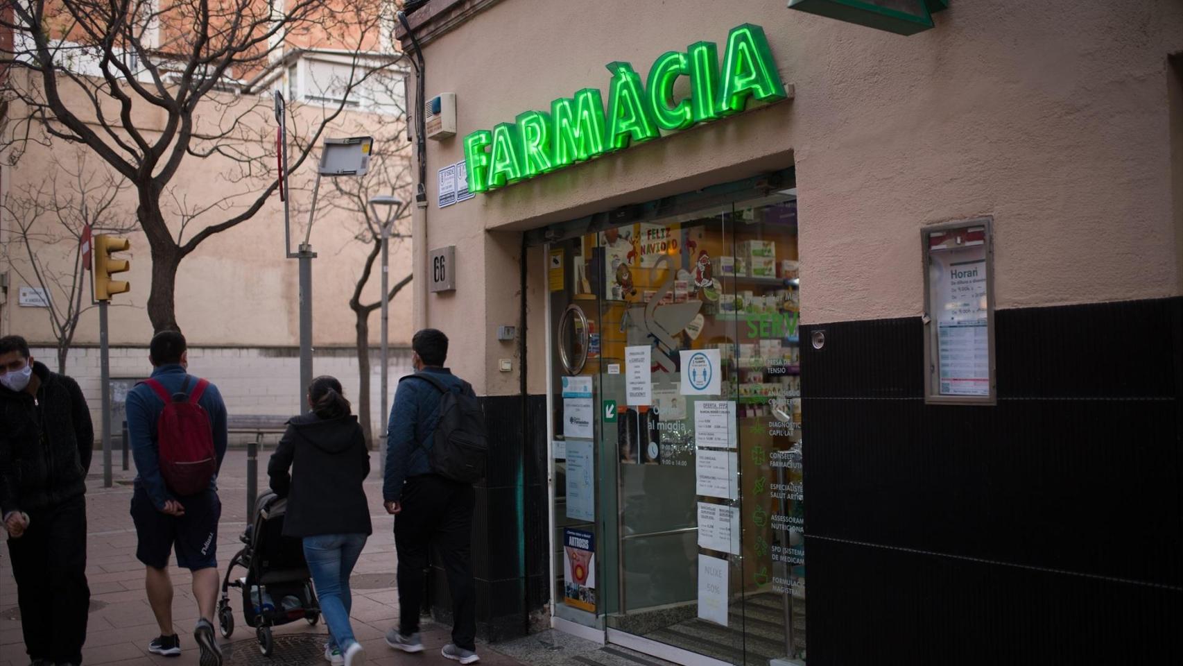 Varias personas pasan al lado de una farmacia, en Barcelona, en una foto de archivo