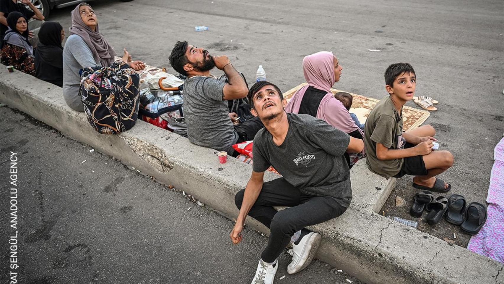 Varias personas miran hacia el cielo con inquietud durante un ataque israelí con drones mientras buscan refugio lejos de los edificios del barrio Dahiyeh, en Beirut. Los aviones y drones suelen volar a baja altura, lo que provoca miedo y angustia. Líbano, 29 de septiembre de 2024