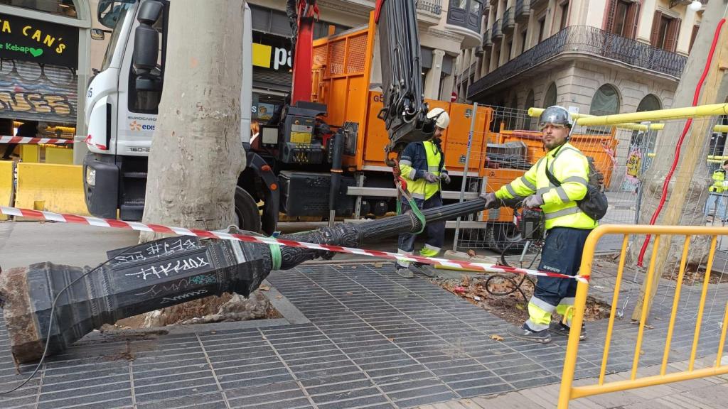 Un operario retira los característicos faros de La Rambla de Barcelona